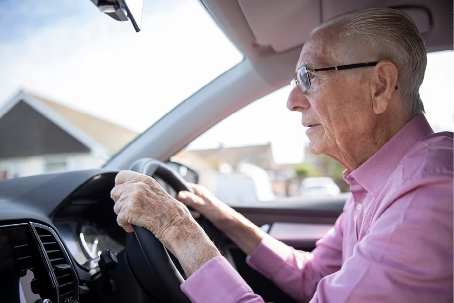 Elderly Man in Pink Shirt in Driving Seat of a car