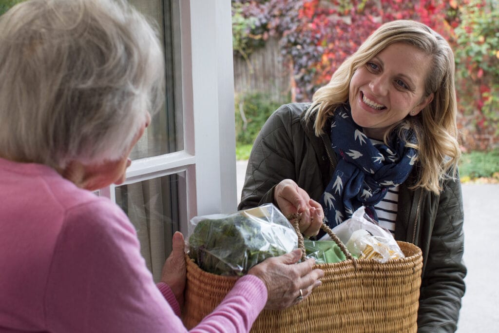 Woman delivering groceries to her elderly neighbour.