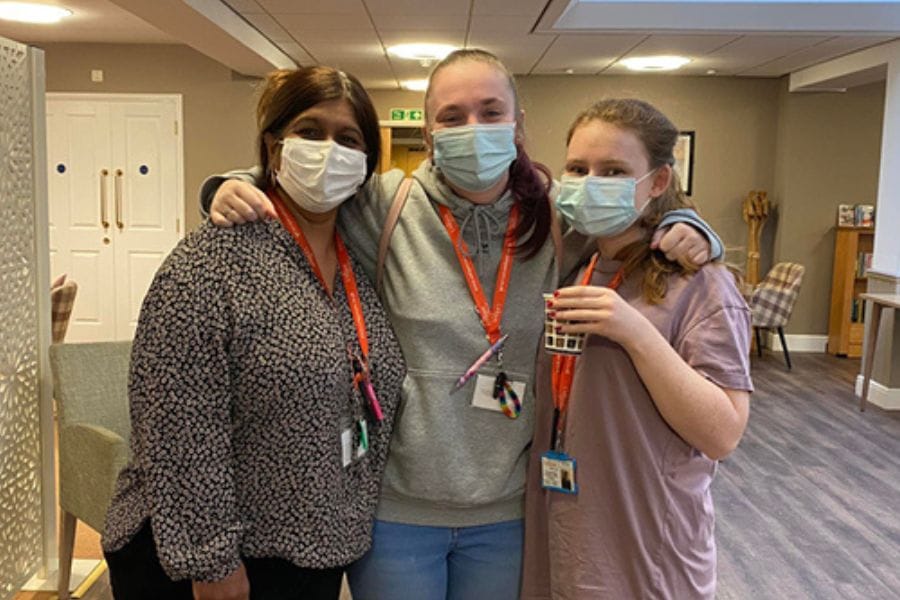 Three colleagues at Briar Croft stand with their arms around one another.