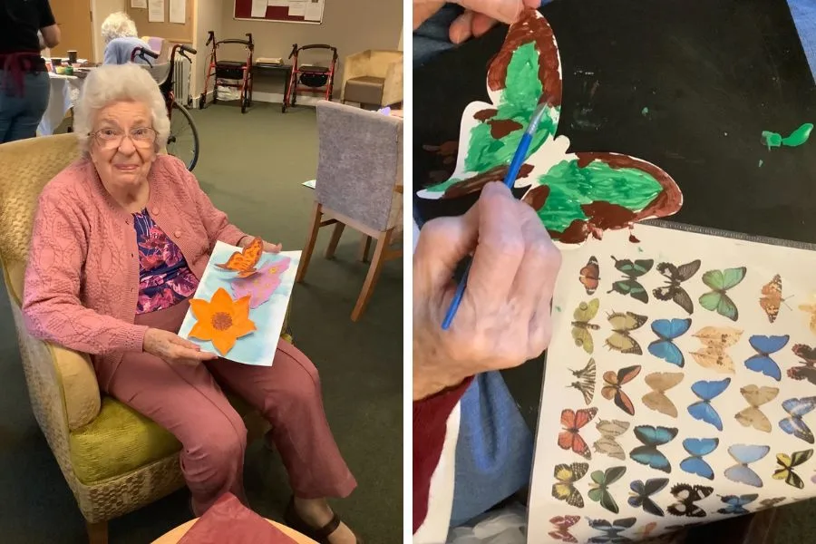 Two split images: Pat sits smiling in an armchair, wearing a pink cardigan and presenting her flower painting. The right image shows a painted cut out of a butterfly with a sheet of colourful smaller butterflies.