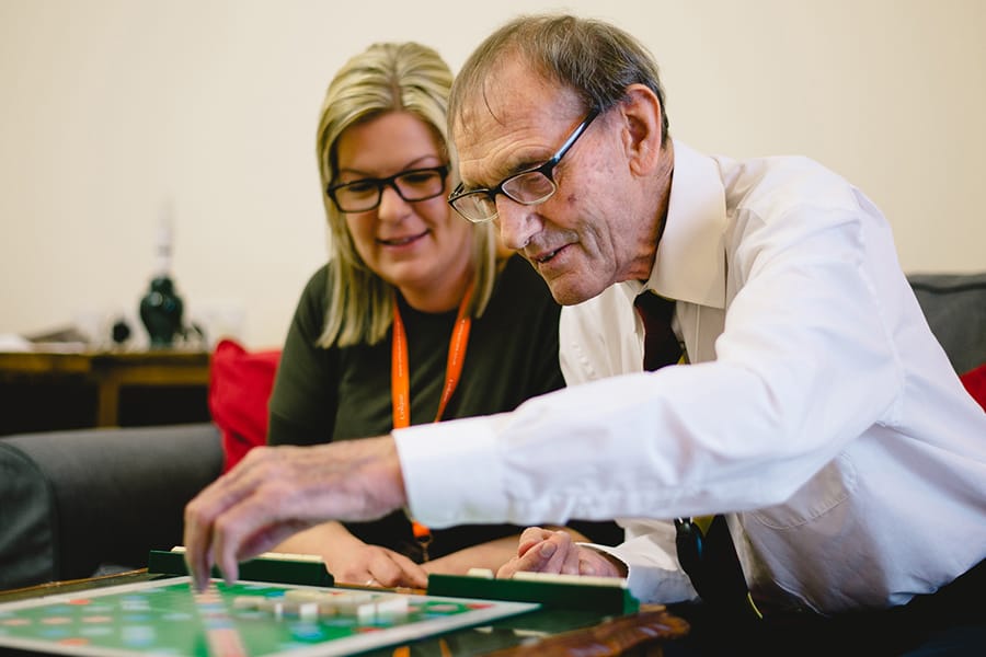 client playing scrabble with Caregiver under conditions supported by 24 hour live-in care