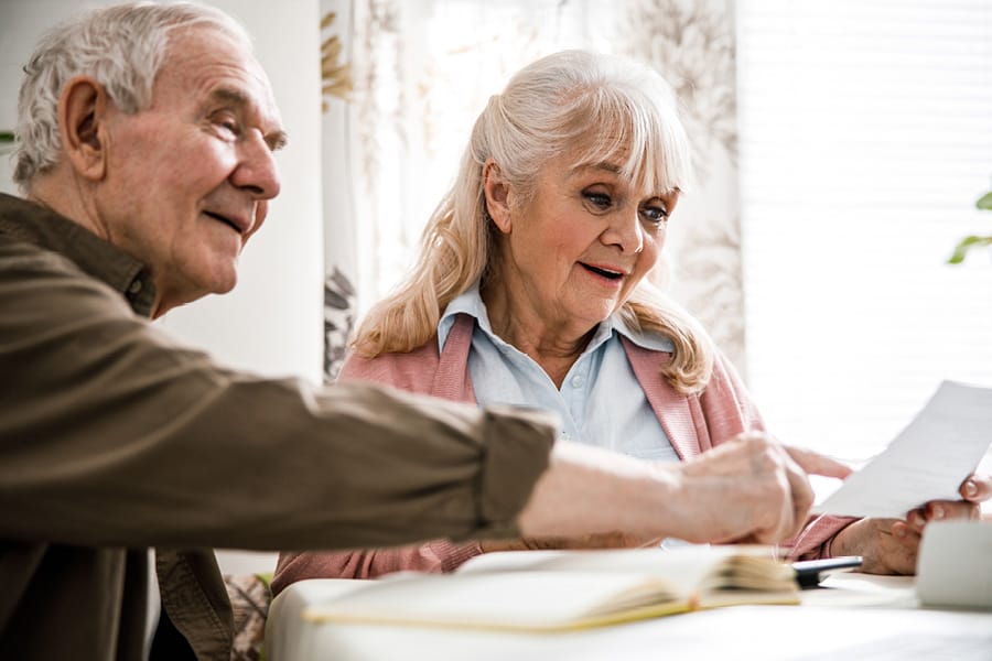 Older couple sat discussing round a table on the section for cost of live-in care