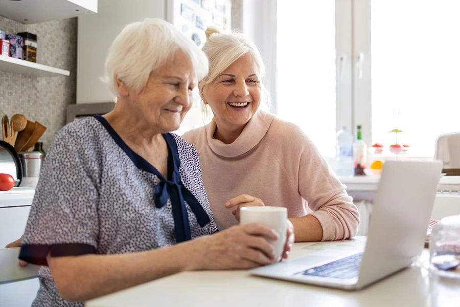 older lady and caregiver looking at costs of care on computer