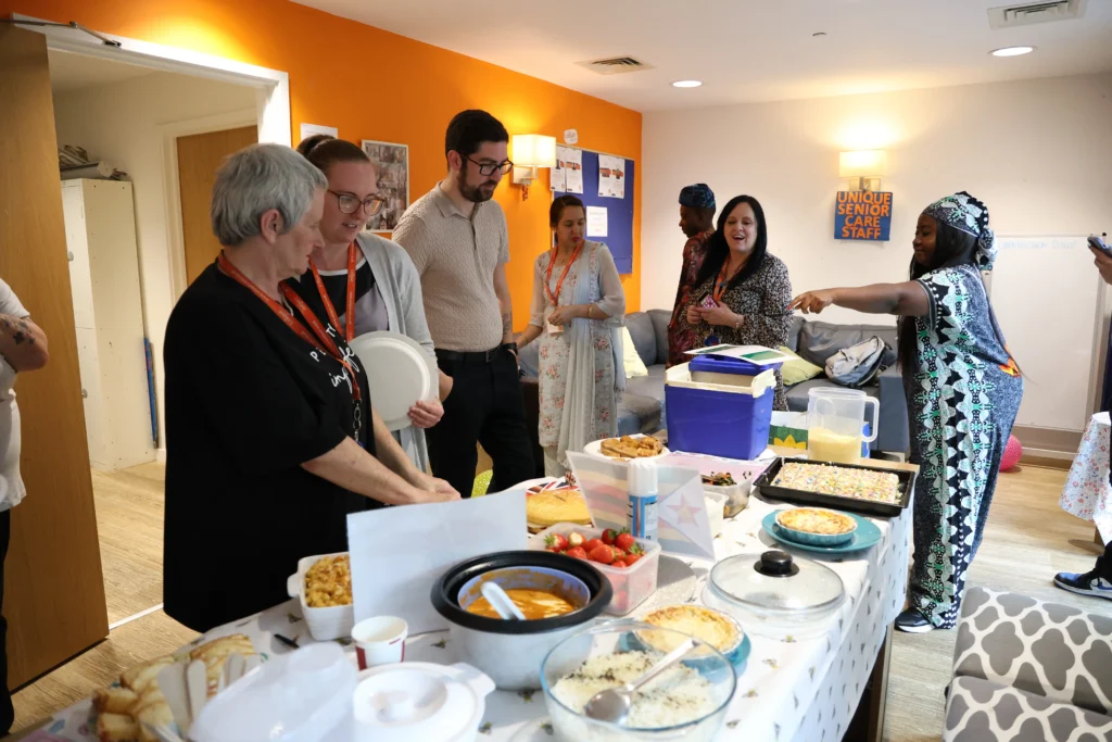 Some of the Unique Senior Care team alongside a table full of multicultural food