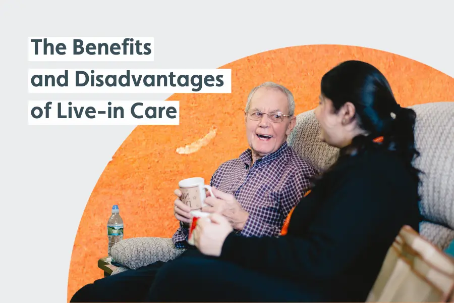 A gentleman and his carer sat smiling while chatting over a cup of tea