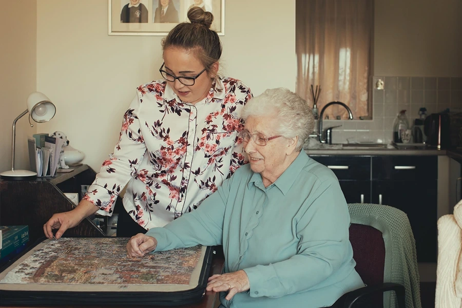 An image of a caregiver and an elderly woman working on a puzzle together illustrates the engagement activities discussed in the "What to Look for in a Live-in Provider" section in Herefordshire.