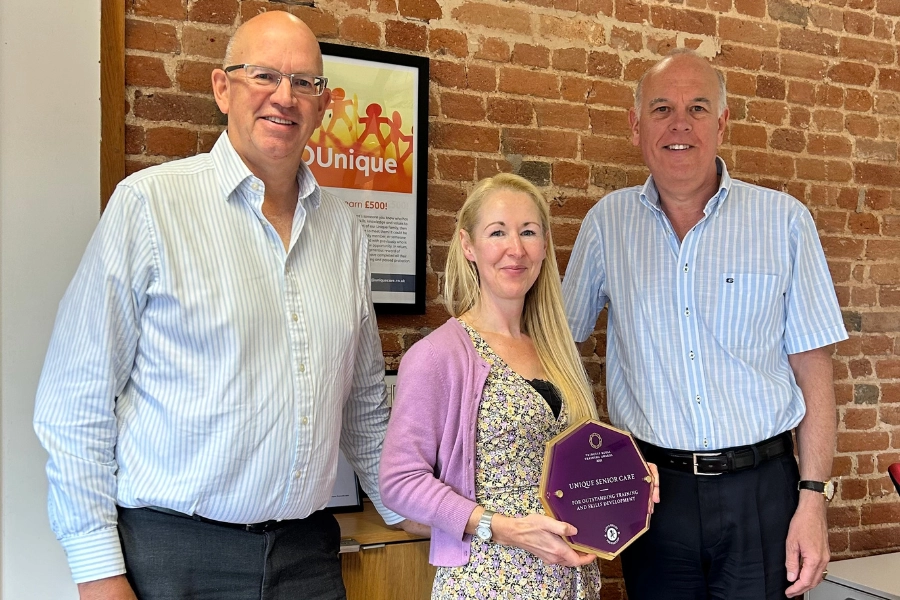 Phil Maundrill, Director, Jo Cleary, Learning and Development Manager, and Phil Wright-Howarth, Director, standing together, smiling and holding their Princess Royal Training Award from 2021.