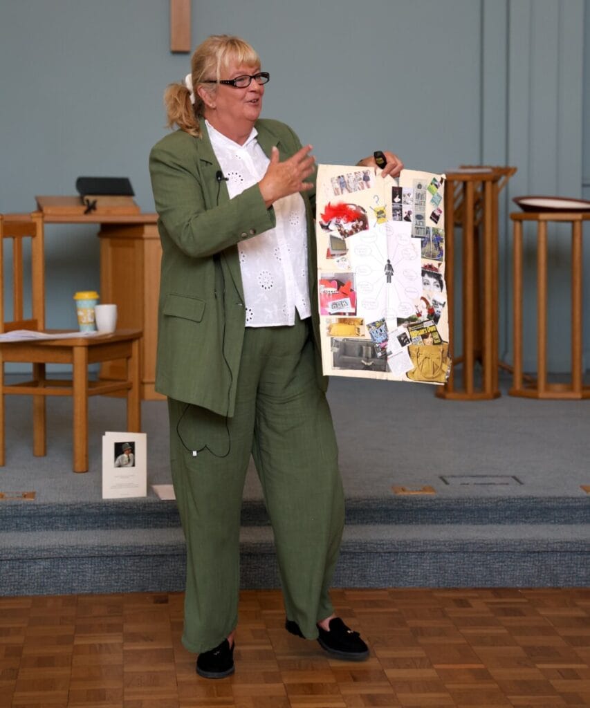 Jayne Vale, dressed in a green suit showing a visual aid while speaking to a group at the Family Dementia Workshop.